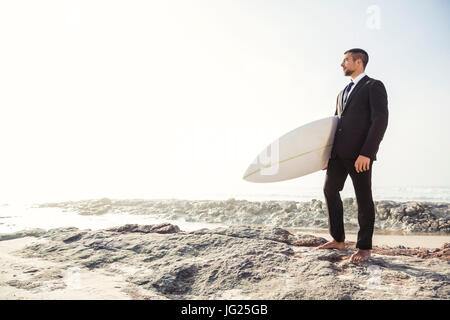 Der Unternehmer hält ist Surfbrett nach einem langen Tag der Arbeit Stockfoto