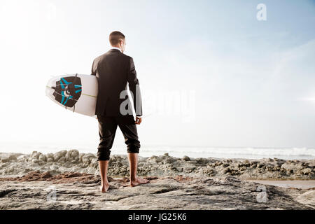 Der Unternehmer hält ist Surfbrett nach einem langen Tag der Arbeit Stockfoto