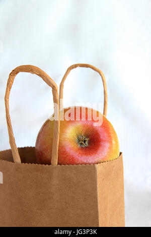 Ein Apfel in eine braune Papiertüte. Stockfoto