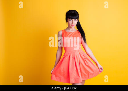 Mädchen in orange Kleid auf einem gelben Hintergrund Stockfoto