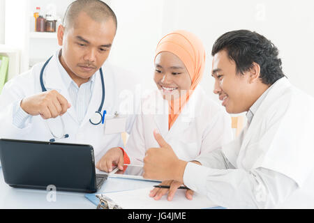 Gruppe von Ärzten diskutieren bei Treffen im Krankenhaus Büro- und zeigt Daumen oben. Südostasiatische medizinische Muslime. Stockfoto