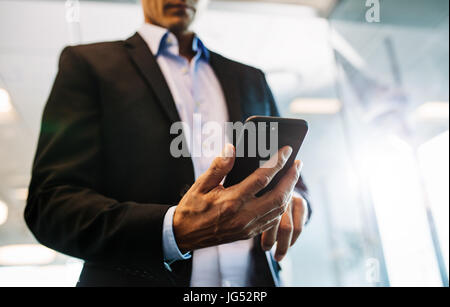 Nahaufnahme von männlichen Händen lesen Ext Nachricht auf Smartphone. Geschäftsmann Mann Hand mit Handy im Büro. Stockfoto