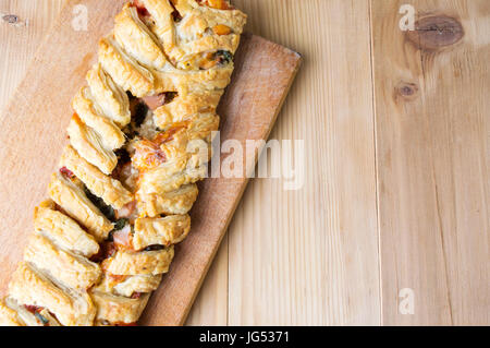 Blätterteig mit Pizzazutaten und in Scheiben geschnittenen Zwiebeln Stockfoto