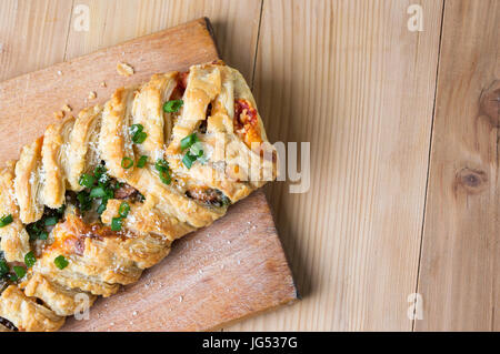 Blätterteig mit Pizzazutaten und in Scheiben geschnittenen Zwiebeln Stockfoto