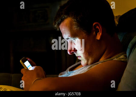 Ein junger Mann eine SMS auf sein Smartphone, Sussex, UK Stockfoto