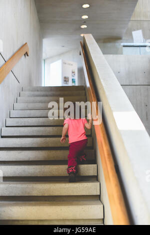 Ein kleines Mädchen klettert die Treppe in eine Kunstgalerie. Stockfoto