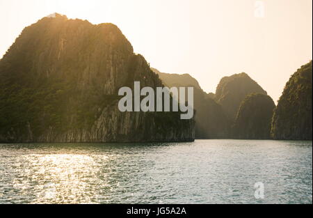 Sonnenuntergang hinter den Kalksteinfelsen der Halong Bucht in Vietnam Stockfoto