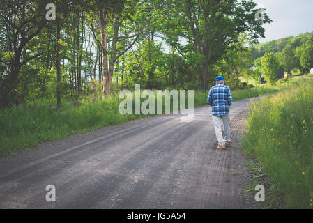 Ein älterer Mann geht alleine auf einer Landstraße. Stockfoto