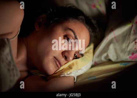 Porträt der jungen Frau mit Tablet im Bett. Mädchen Lesen von digital-Tablette am Abend Stockfoto