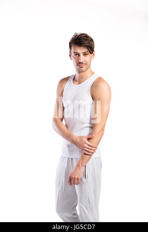 Hübsche Hipster Fitness Mann in weißen Tank-Top Shirt und graue Jogginghose. Studio auf weißem Hintergrund gedreht. Stockfoto