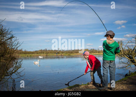 Zwei Jungen fangen und Verrechnung ein Fisch in einem See, England, Großbritannien Stockfoto