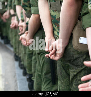 Hinten Sie Ansicht von. Soldaten in Tarnung Uniformen stehen auf die Manifestation, die Hände hinter dem Rücken. Stockfoto