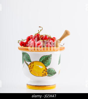 Rote Johannisbeere Beeren gestapelt in handgefertigte farbige Keramikschale isoliert auf weißem Hintergrund Stockfoto
