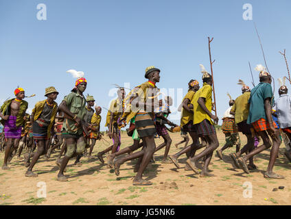 Männer, die im Einklang mit Waffen ausgeführt, während der Zeremonie stolz Ochsen in den Dassanech Stamm, Turkana County, Omorate, Äthiopien Stockfoto