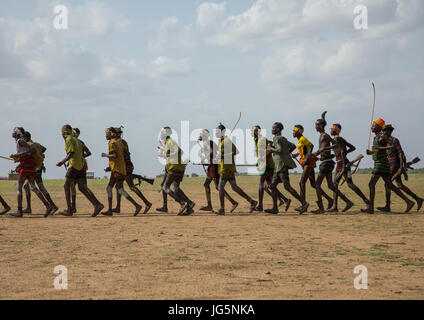 Männer, die im Einklang mit Waffen ausgeführt, während der Zeremonie stolz Ochsen in den Dassanech Stamm, Turkana County, Omorate, Äthiopien Stockfoto