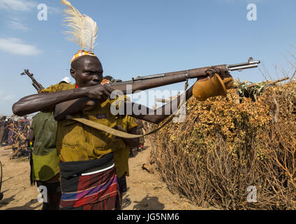 Mann mit einer Kalaschnikow schießen, während der Zeremonie stolz Ochsen in den Dassanech Stamm, Turkana County, Omorate, Äthiopien Stockfoto