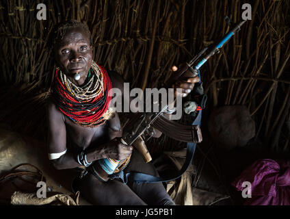 Nyangatom Stamm Frau hält eine Kalaschnikow in ihrer Hütte, Omo-Tal, Kangate, Äthiopien Stockfoto