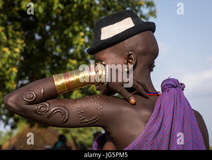 Schöne junge Frau mit einem Hut und Armbänder während der Zeremonie dicke Männer des Stammes Bodi, Omo-Tal, Hana Mursi, Äthiopien Stockfoto