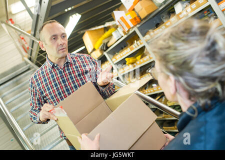junger Verkäufer im Supermarkt mit senior client Stockfoto