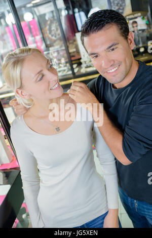 Frau versucht Halskette mit ihrem Ehemann in einem Schmuck-shop Stockfoto