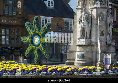 Floral Sonne Symbol Skulptur und bunten Blumenbeet vor Banbury cross, im Licht frühen Morgens. Oxfordshire, England Stockfoto