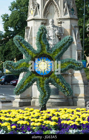 Floral Sonne Symbol Skulptur und bunten Blumenbeet vor Banbury cross, im Licht frühen Morgens. Oxfordshire, England Stockfoto