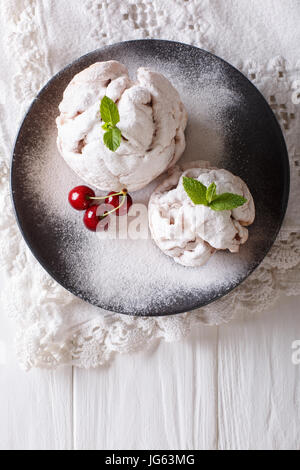 Schneeball-Torte dekoriert mit Minze und Kirsche auf einem Teller. vertikale Ansicht von oben Stockfoto