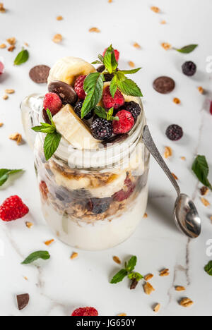 Sommer Früchte Beeren Frühstück. Gesunde Bananensplit Frühstück mit Frischkäse, Himbeeren, Brombeeren, Minze, weiß und rosa Schokolade. Im Maurer ja Stockfoto