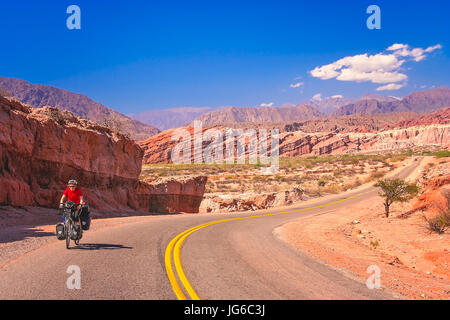 Frau, Radfahren auf der leeren Straße nach Cafayate in den abgelegenen Teil von Nord-West-Argentinien Stockfoto