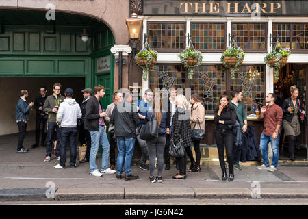 Menschen mit Gespräch mit Getränken in der hand vor The Harp Pub, London, UK Stockfoto