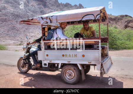 Hormuz Insel, Provinz Hormozgan, Iran - 17. April 2017: Touristen machen einen Rundgang durch natürliche Sehenswürdigkeiten der Insel in einem dreirädrigen Motorrad van. Stockfoto