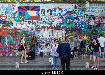 Viele Touristen und ein Straßenmusikant an der John-Lennon-Mauer in Prag. Es ist eine Wand mit Stücken von songtexte von Beatles Songs und John Lennon inspirierten Graffiti. Stockfoto
