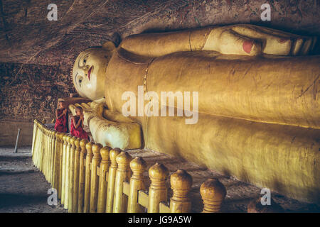 Buddhistischer Novize / kleinen Mönch / junger Mönch anbeten große schöne liegende Buddha-Statue in Phowintaung Höhle Monywa Myanmar Stockfoto