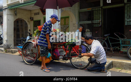 Ein Mann führen Sie eine Reparatur an einem Cyclo-Taxi in Georgetown, Penang, Malaysia Stockfoto