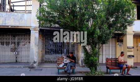 Zwei chinesische Männer sitzen auf Bänken Straße am frühen Abend in Georgetown, Penang, Malaysia Stockfoto