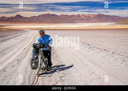 Frau Radrennfahrer kämpfen und schieben ihr Fahrrad auf Wellpappe Sandweg im Altiplano in Bolivien Stockfoto