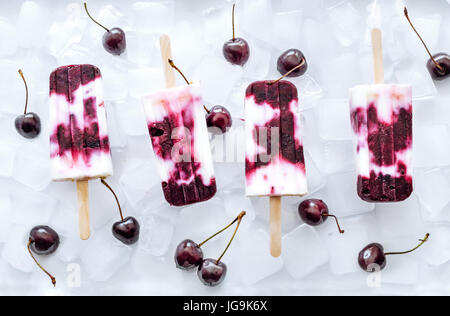 Joghurt und Kirschen Eis am Stiel auf Eiswürfel. Erfrischendes Sommer-Dessert. Stockfoto