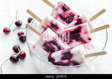 Gesunde Sommer-Dessert. Hausgemachte Kirsche Joghurt Eis Eis am Stiel in Schüssel geben. Stockfoto