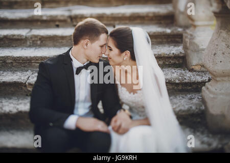 Braut und Bräutigam sitzen auf Steinstufen Stockfoto