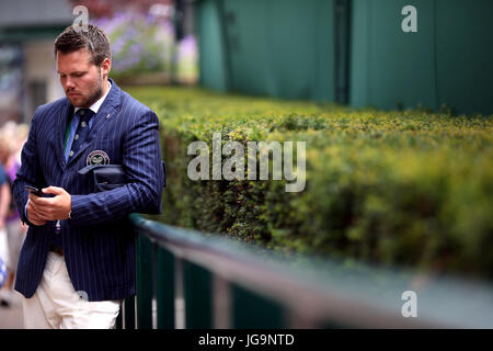 Ein Schiedsrichter auf seinem Handy außerhalb eines Gerichtes am zweiten Tag der Wimbledon Championships in The All England Lawn Tennis and Croquet Club, Wimbledon. Stockfoto