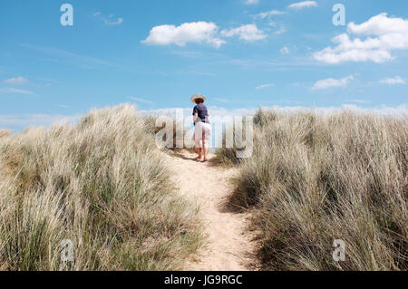 Southwold Suffolk UK Juni 2017 - Frau mit Sonnenhut auf Southwold Strand und Dünen Foto von Simon Dack Stockfoto