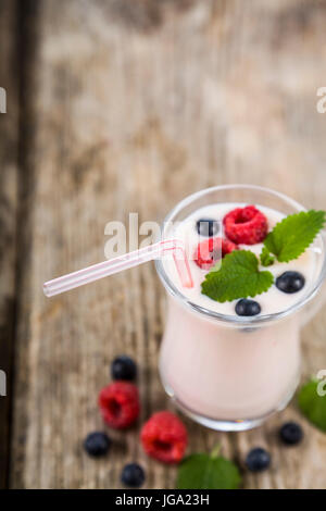 Smoothies oder Joghurt mit frischen Beeren auf einem Holztisch. Milchshakes mit Himbeeren, Brombeeren, Aprikosen und Minze. Stockfoto