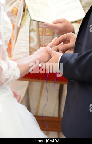 Braut ein Bräutigam tauschen ihre Eheringe in Kirche, Priester hielt Hochzeit Buch Stockfoto