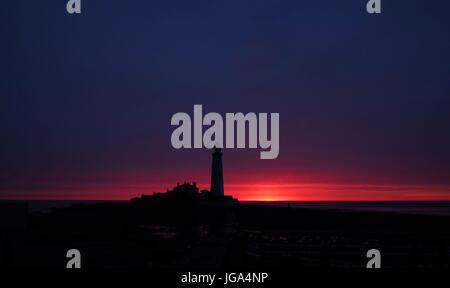 Die Sonne beginnt zu steigen hinter Str. Marys Leuchtturm in Whitley Bay, South Shields. Stockfoto