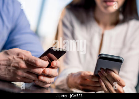 Close-up Teilansicht des jungen Paares mit Smartphones zusammen Lunch Meeting Konzept Stockfoto