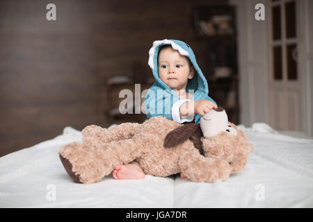 Glückliches Baby junge im blauen Gewand mit Teddybär im Bett spielen Stockfoto