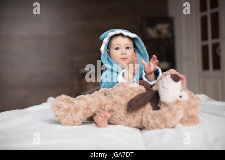 Glückliches Baby junge im blauen Gewand mit Teddybär im Bett spielen Stockfoto