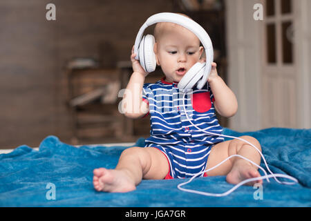 Lustige Babyjungen tragen weiße Kopfhörer Stockfoto