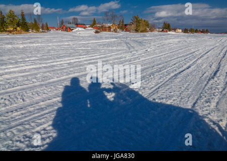 Schatten Sie im Schnee der Menschen auf einem Schneemobil, Lappland, Schweden Stockfoto