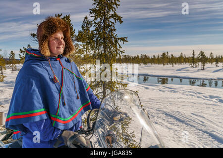 Mann in traditioneller Kleidung der Sami auf einem Schneemobil, Lappland, Schweden Stockfoto